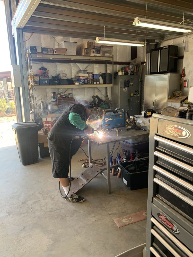 A man is welding a piece of metal in a garage.