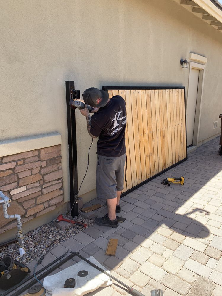 A man is working on a wooden fence in front of a building.