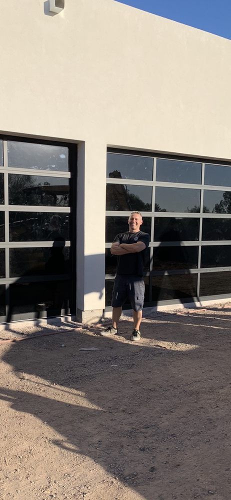 A man is standing in front of a garage door.