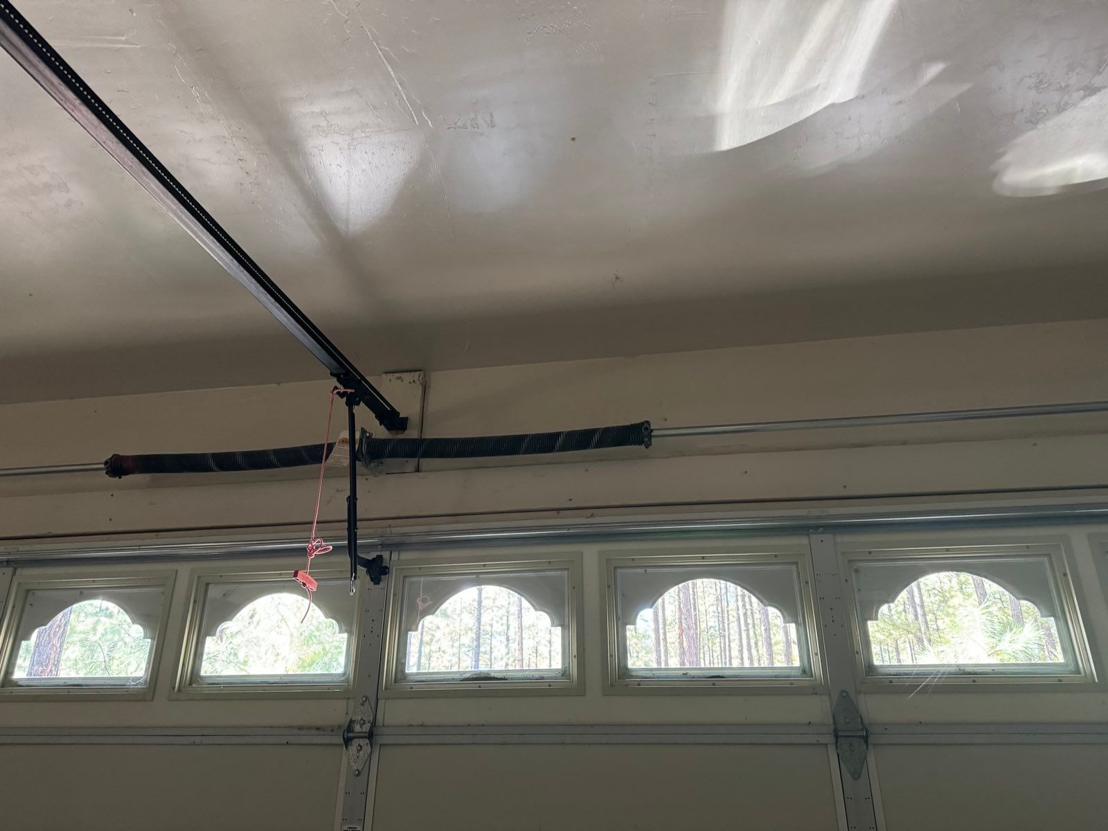 A garage door with a broken spring hanging from the ceiling.