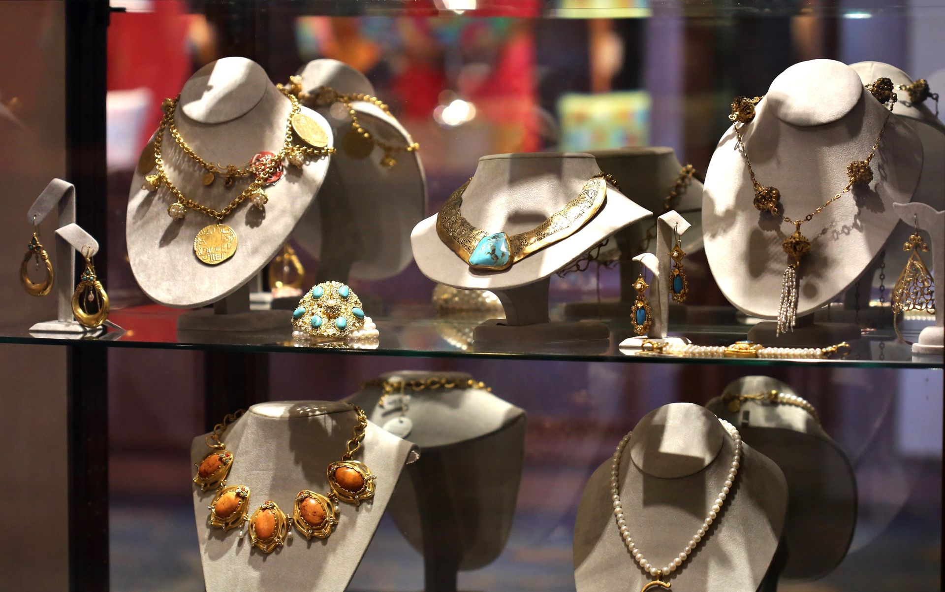 A display case filled with necklaces and earrings on mannequins