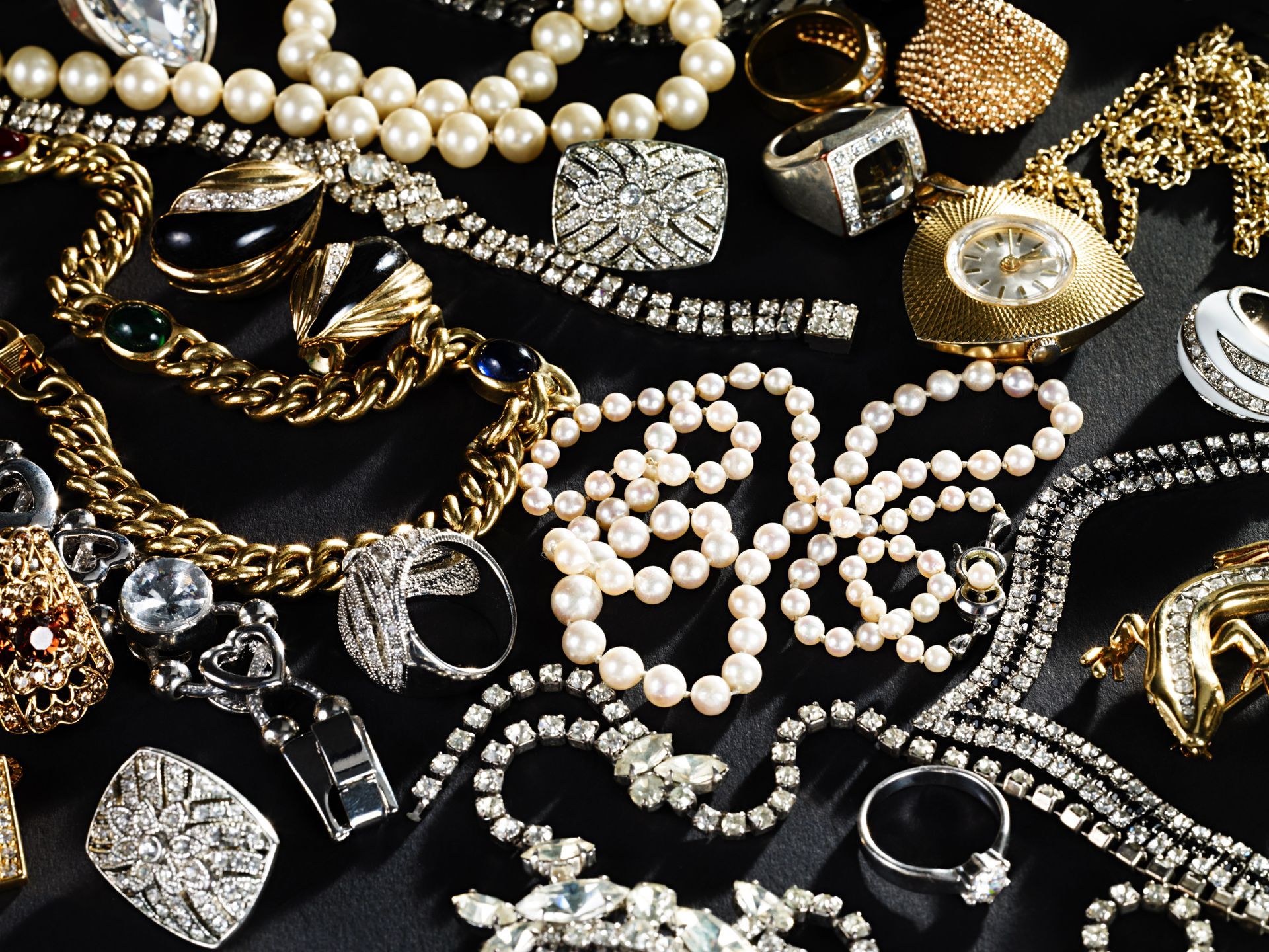 A bunch of jewelry including pearls and rings on a black cloth
