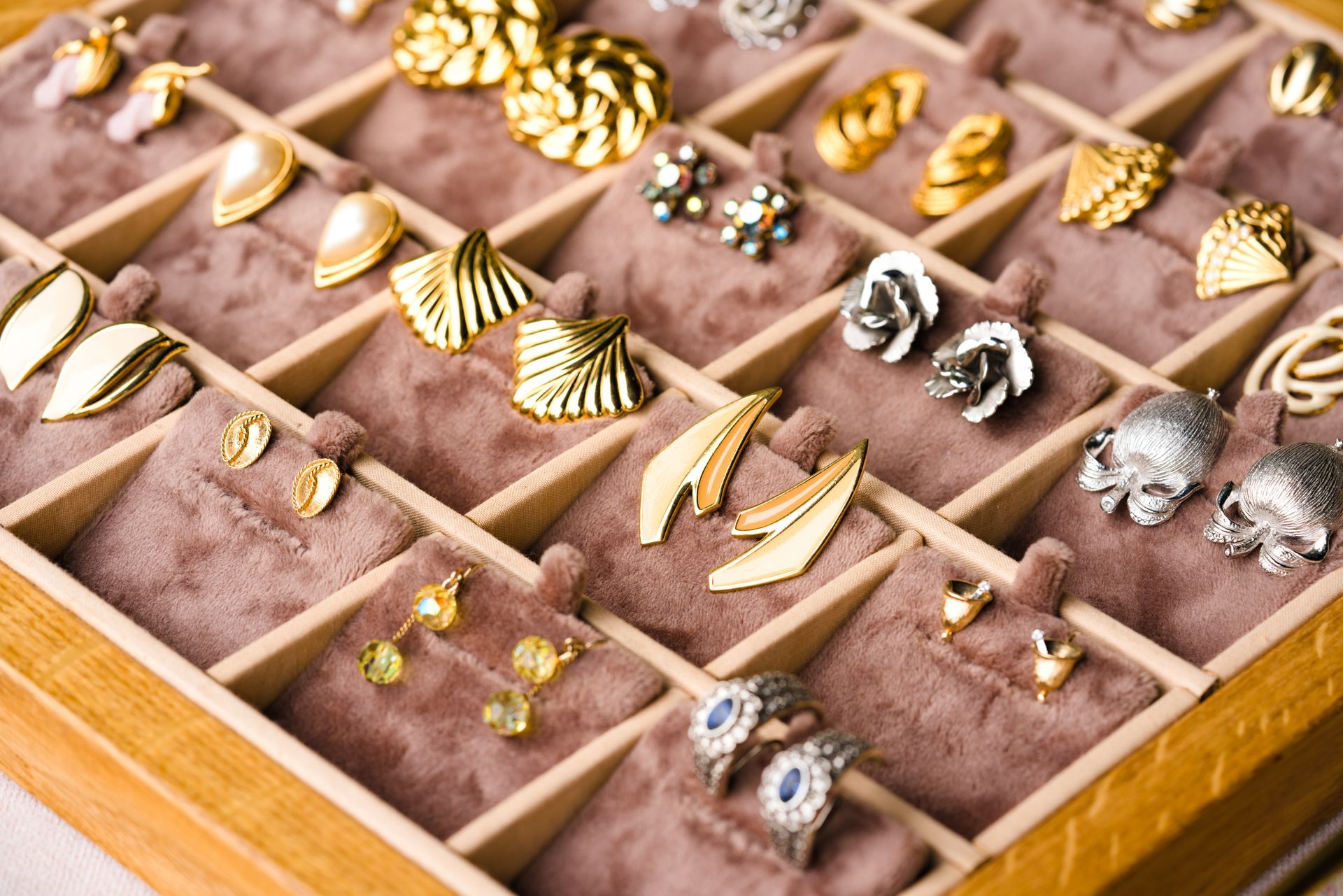 A wooden jewelry box filled with earrings and rings