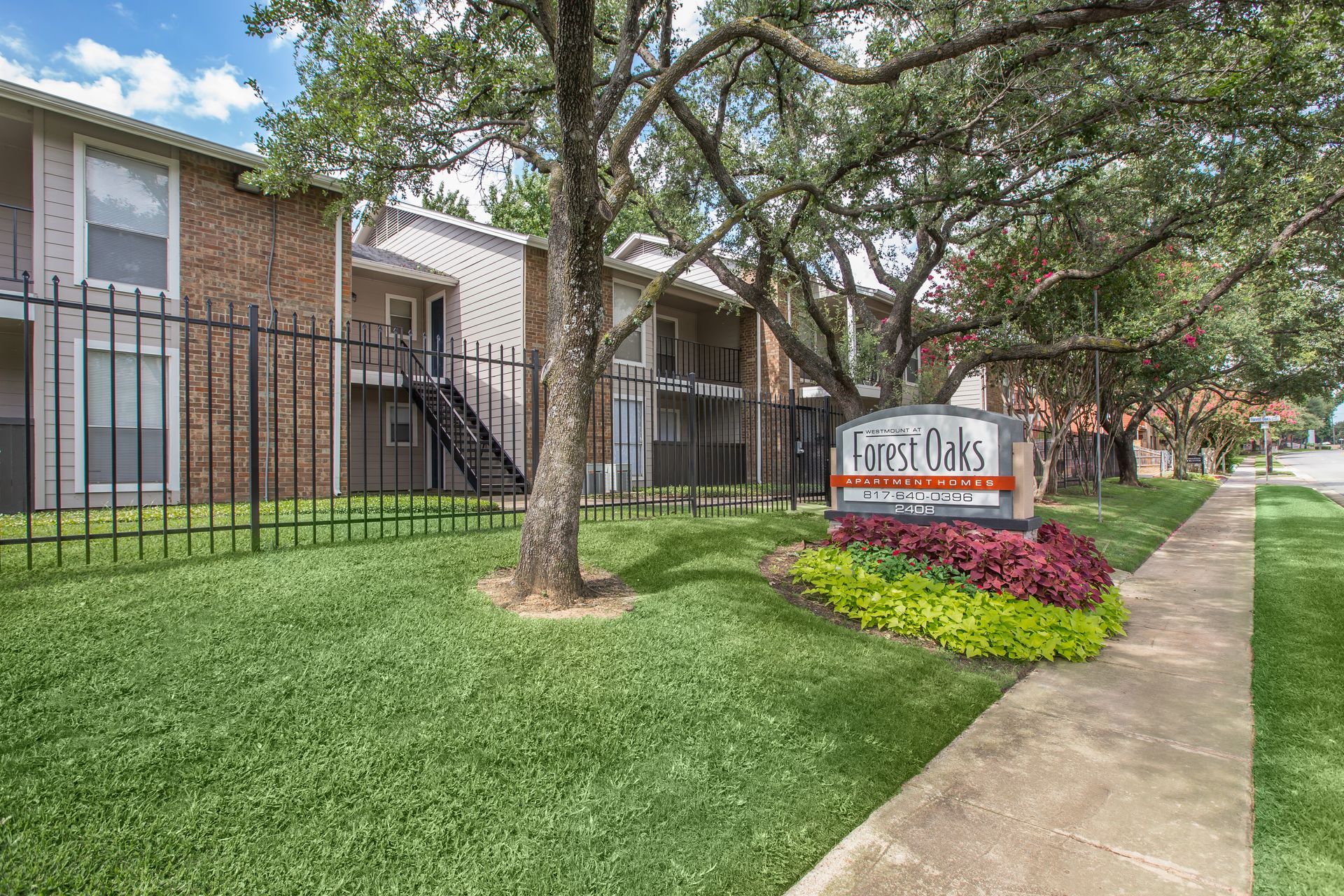 A brick apartment building with a sign in front of it.