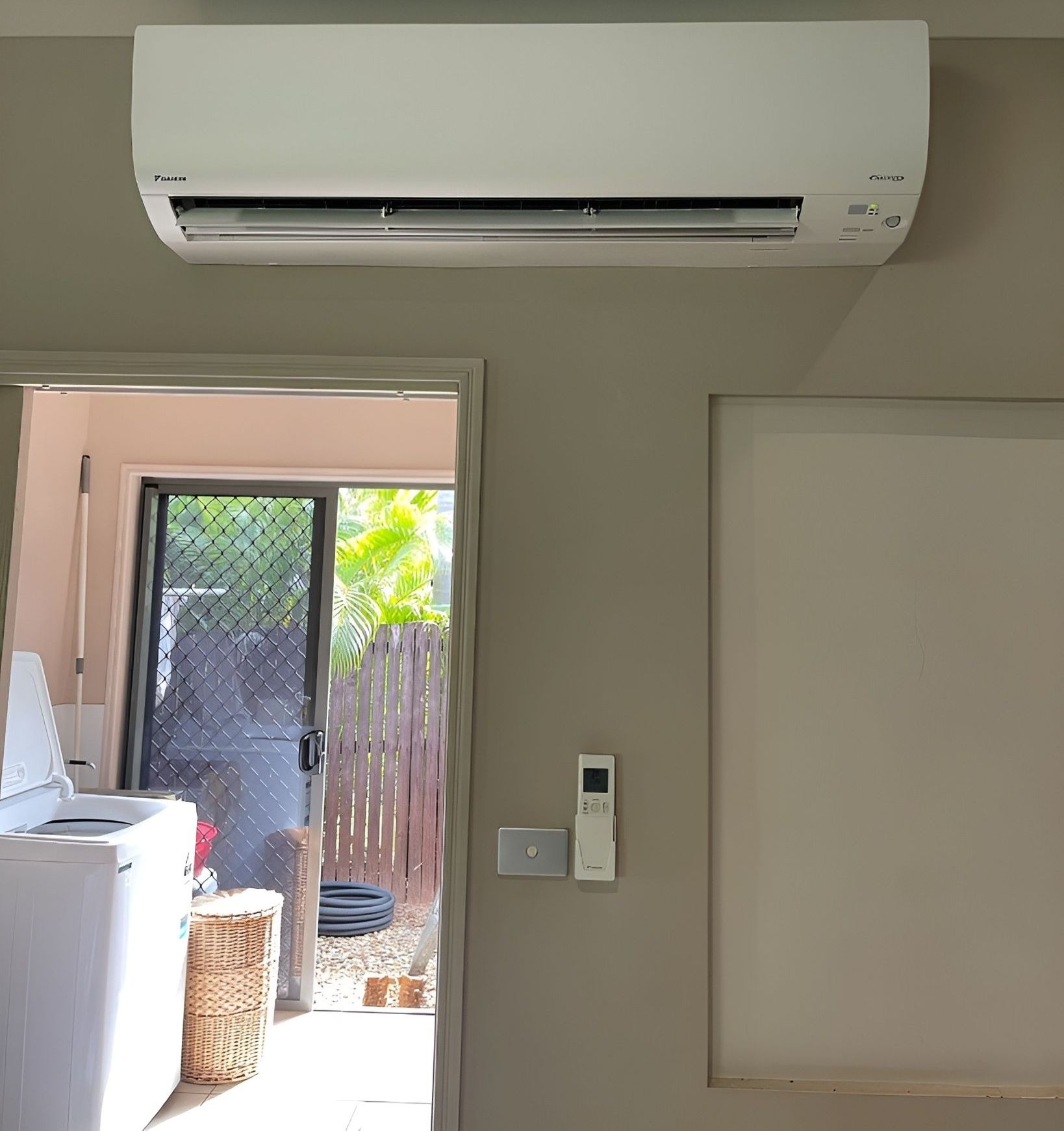 A Room With a Washer and Dryer and a Wall Mounted Air Conditioner — Eclipse Air Conditioning and Refrigeration in Trinity Beach, QLD