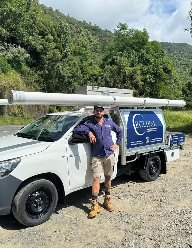 A Man is Standing Next to a White Truck — Eclipse Air Conditioning and Refrigeration in Trinity Beach, QLD