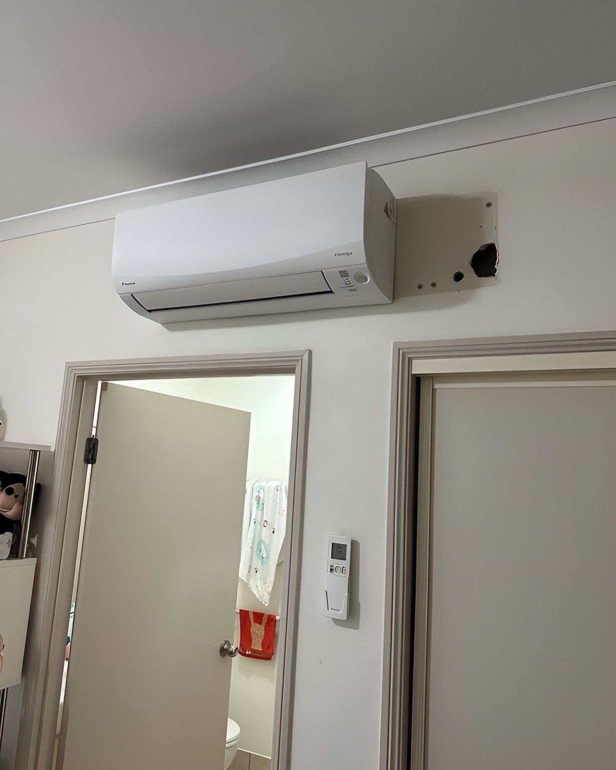 A White Air Conditioner is Hanging From the Ceiling in a Room Next to a Door — Eclipse Air Conditioning and Refrigeration In Palm Cove, QLD