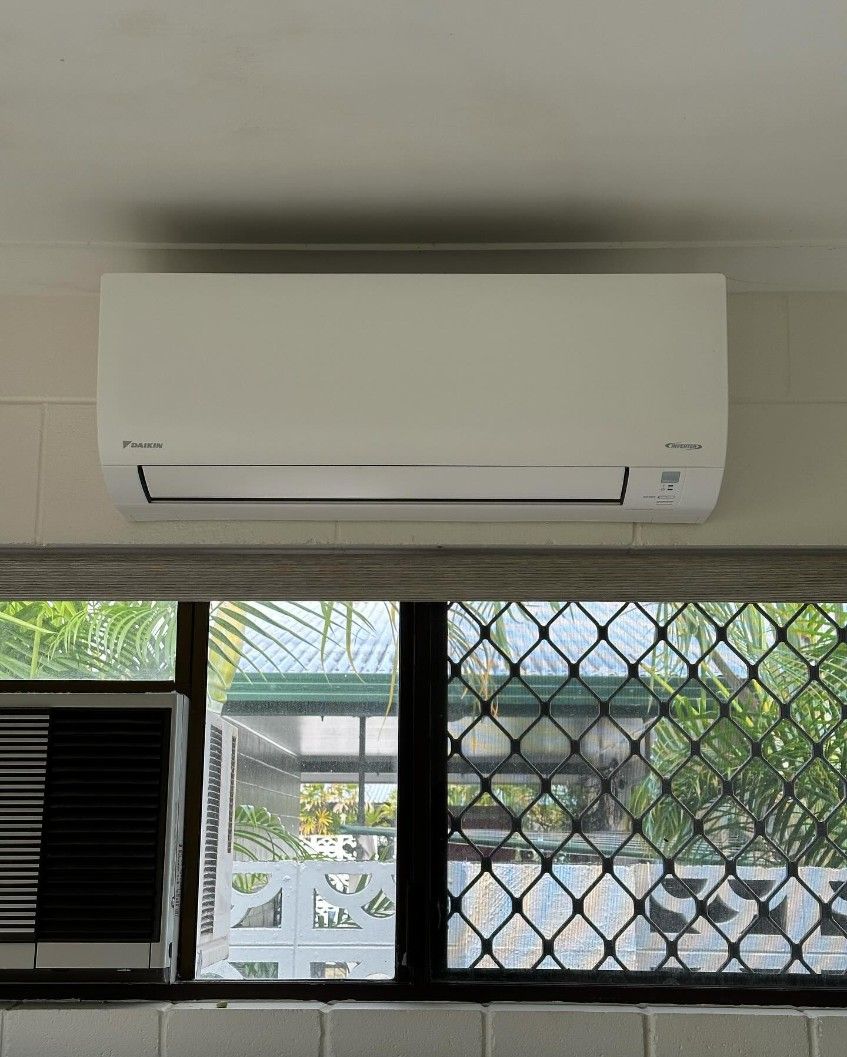 A White Air Conditioner is Hanging From the Ceiling Above a Window — Eclipse Air Conditioning and Refrigeration In Palm Cove, QLD