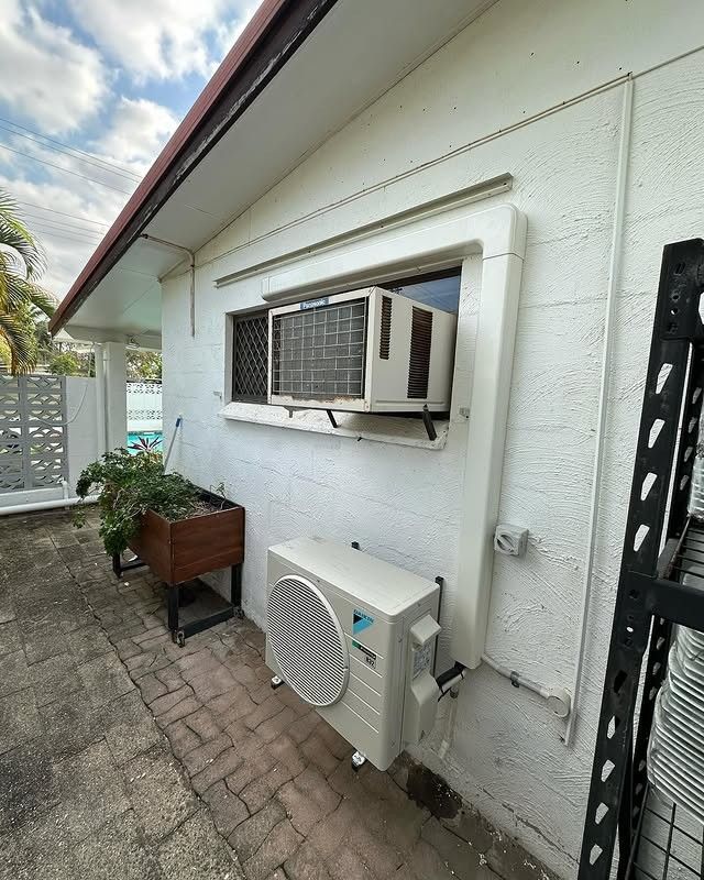 A White House With a Window and an Air Conditioner on the Side of It — Eclipse Air Conditioning and Refrigeration In Palm Cove, QLD