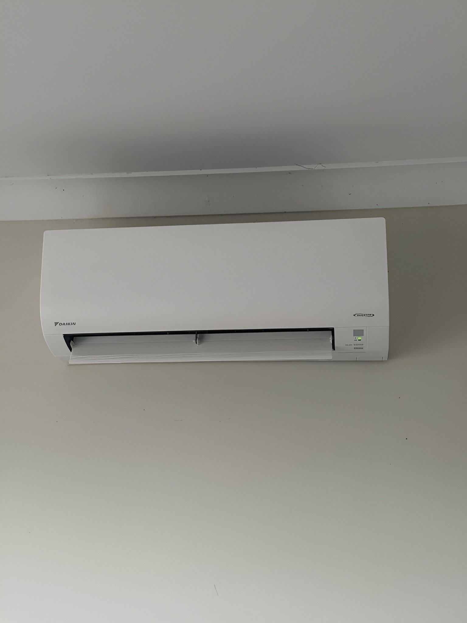 A White Air Conditioner is Hanging on a White Wall — Eclipse Air Conditioning and Refrigeration In Smithfield, NSW