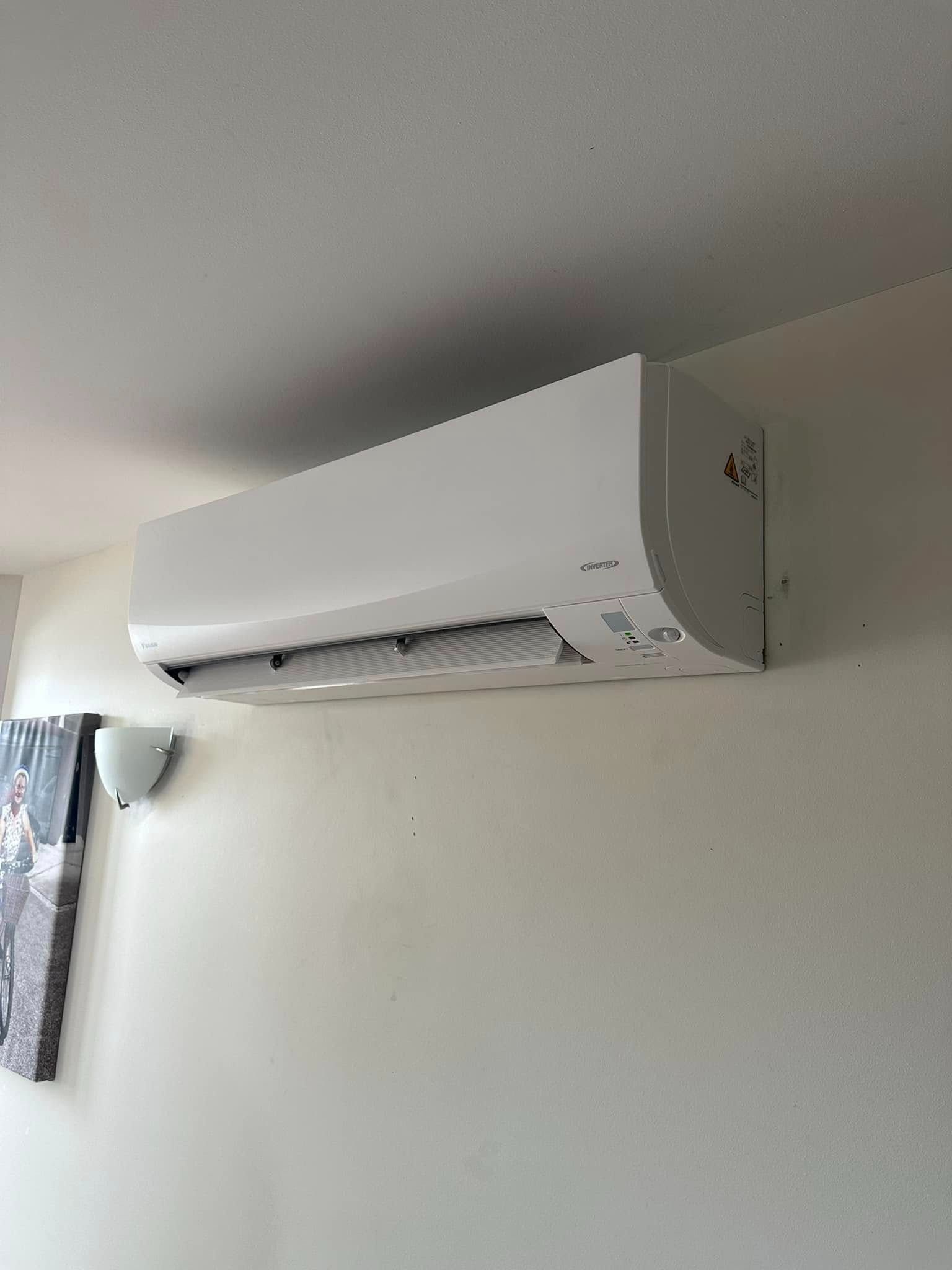 A White Air Conditioner is Hanging From the Ceiling in a Living Room — Eclipse Air Conditioning and Refrigeration In Smithfield, NSW