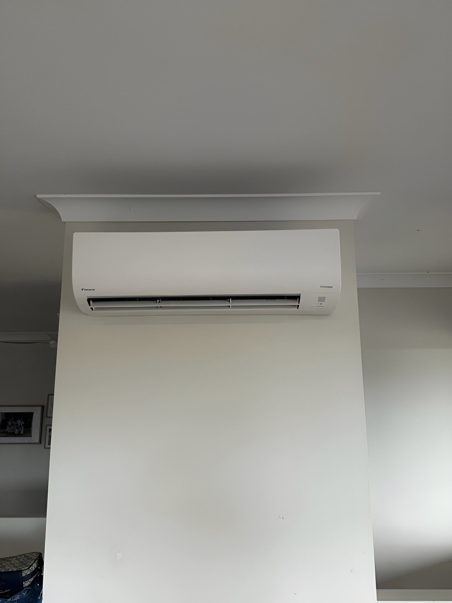 A White Air Conditioner is Mounted on a White Wall in a Living Room — Eclipse Air Conditioning and Refrigeration In Smithfield, NSW