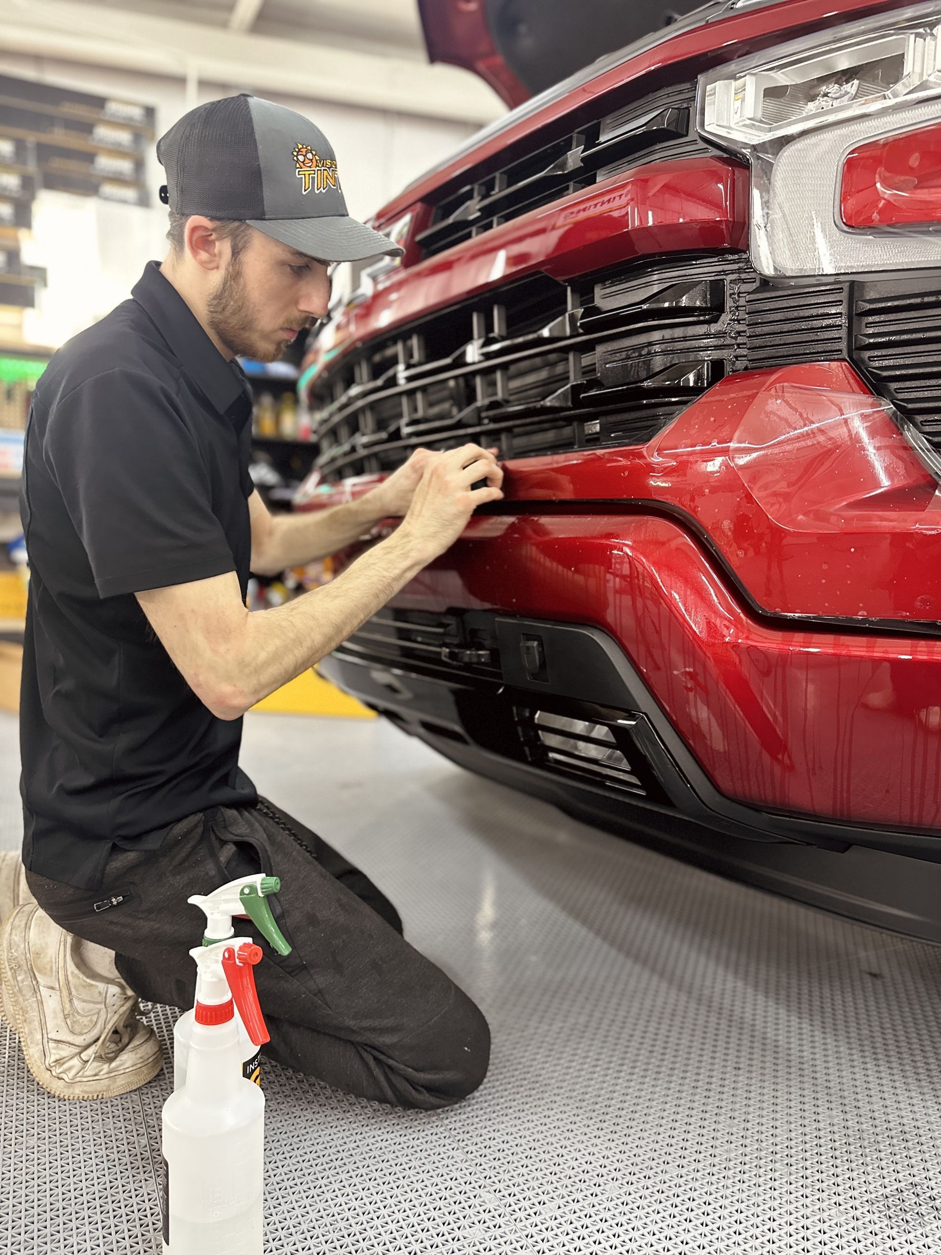 A man is kneeling down in front of a red truck.