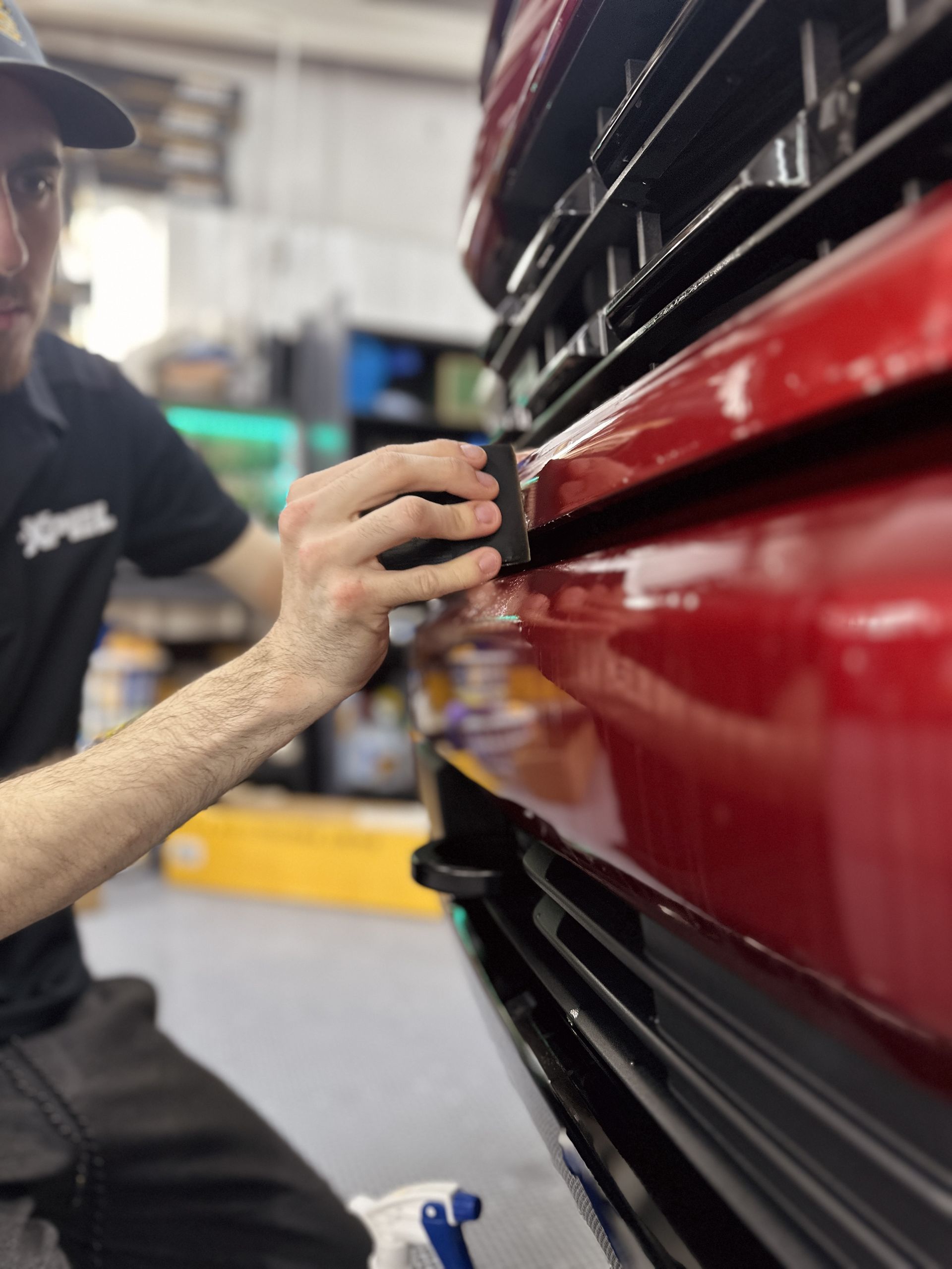 A man is working on the front of a red car