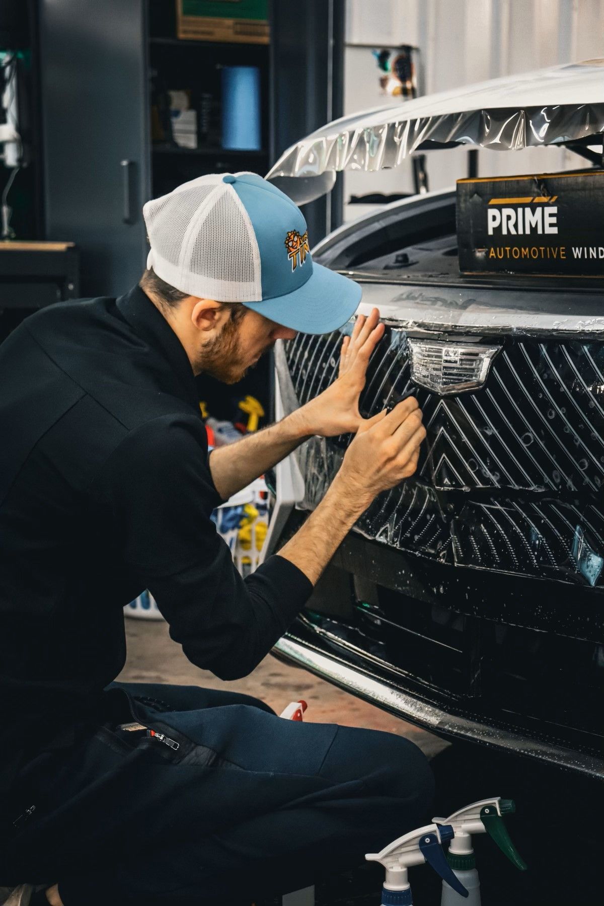 A man is wrapping the front of a car with a protective film.