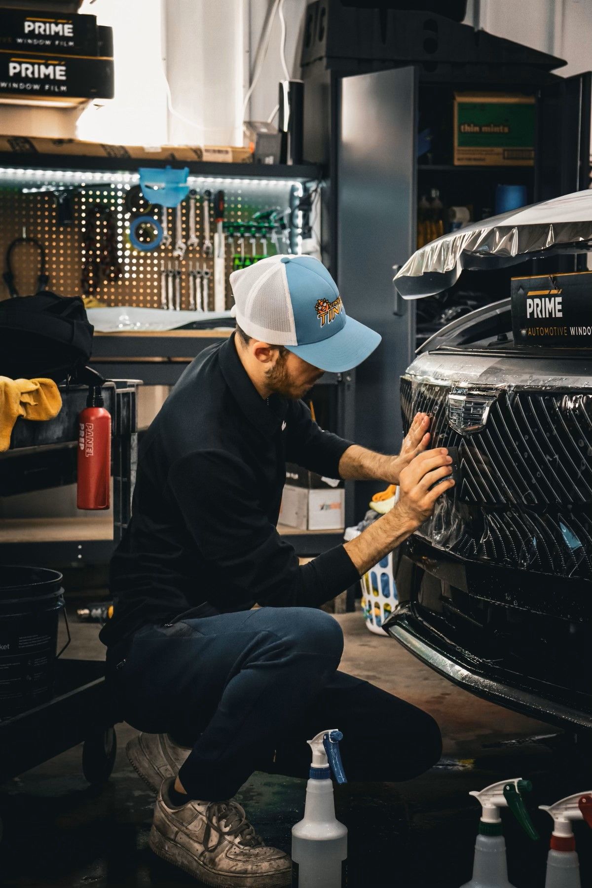 A man is kneeling down in front of a car.
