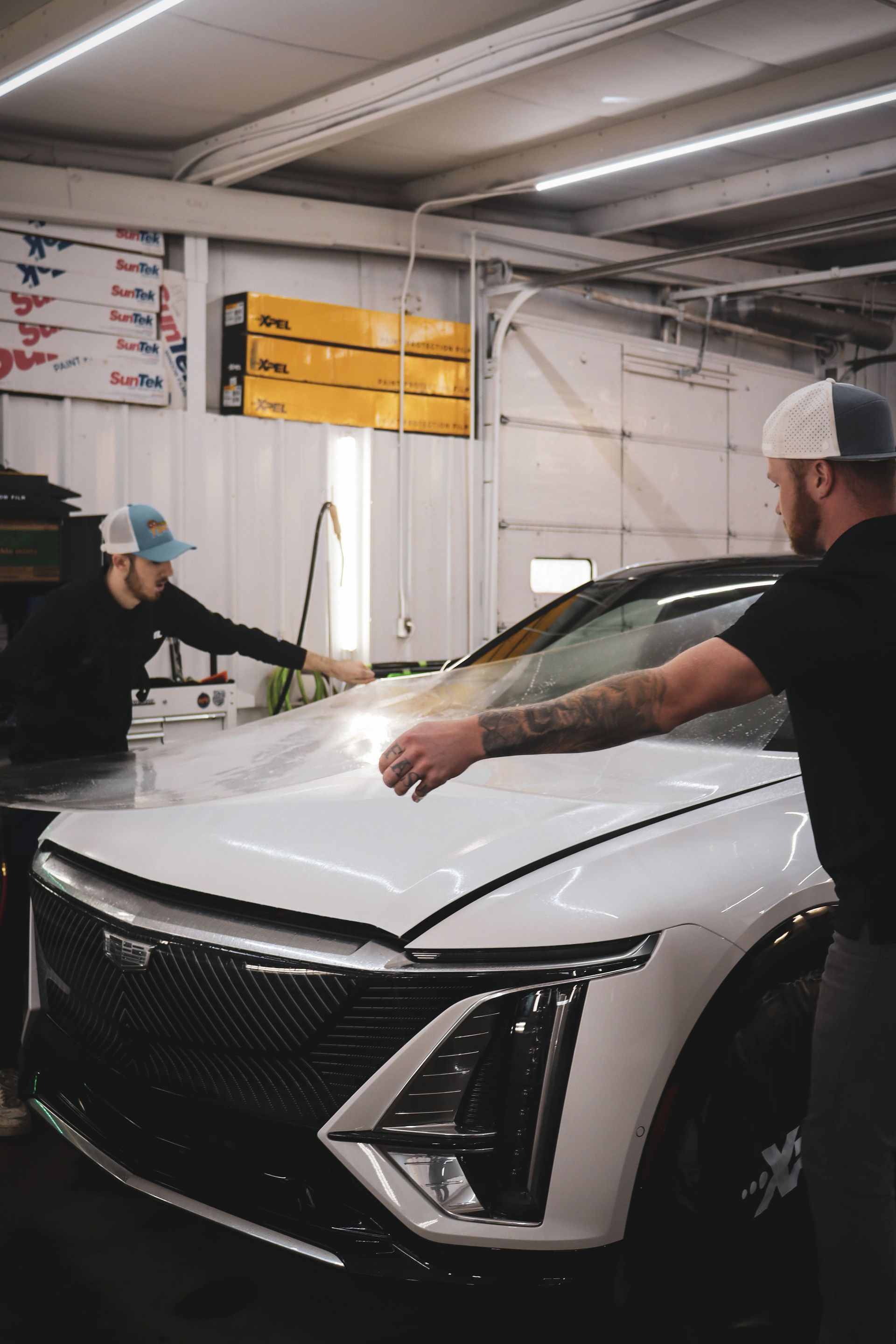 A man is standing next to a white car in a garage.