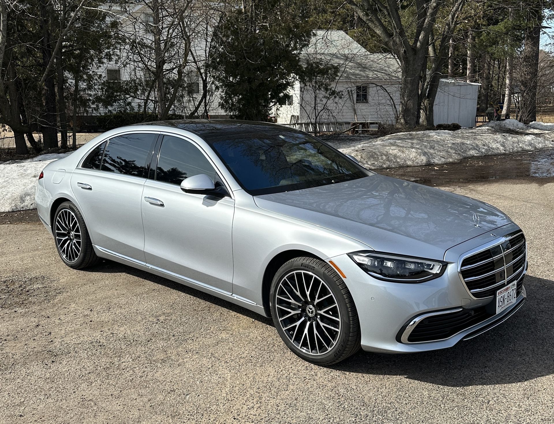 A silver mercedes benz s class is parked in a gravel lot.