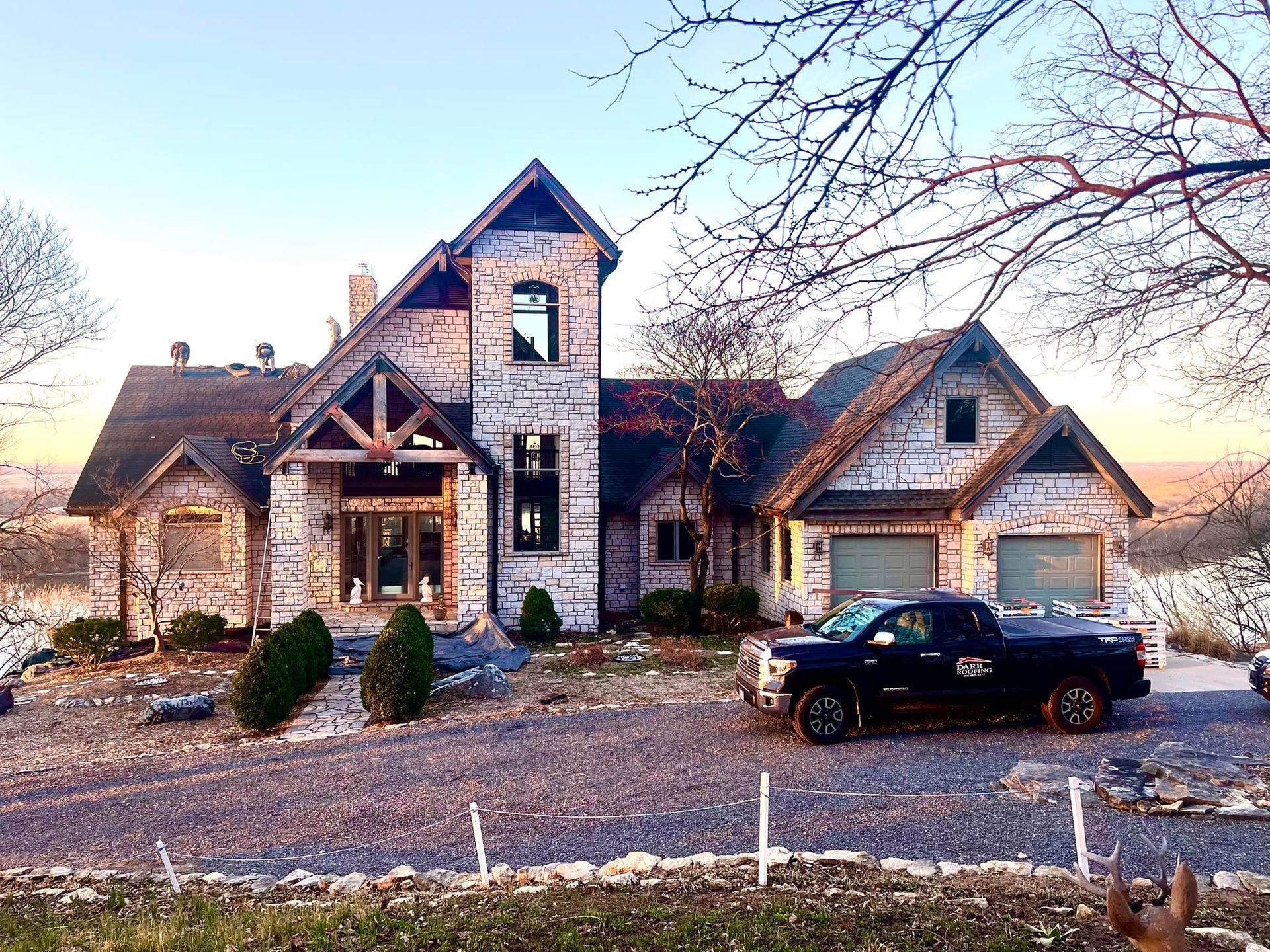 Stone house with a black pickup truck on a gravel driveway.