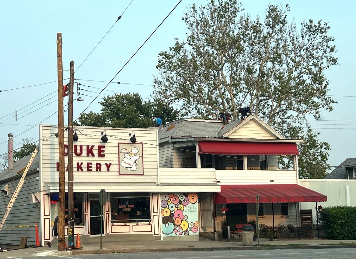 Duke Bakery storefront with red awnings, a colorful donut mural, and power poles.