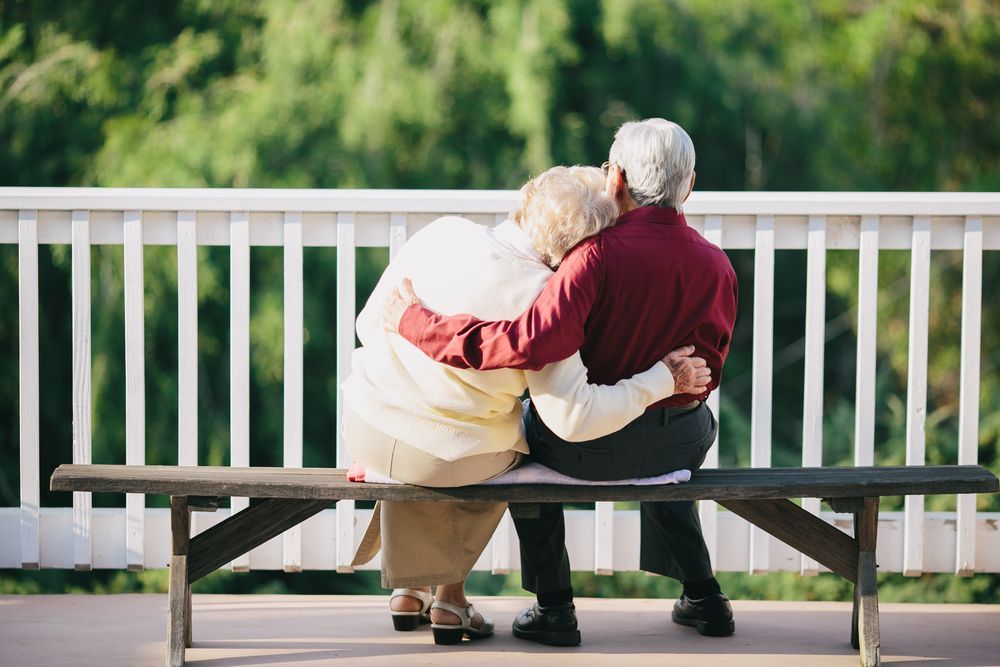 An Elderly Couple Is Sitting on A Dock Looking at A Lake — TJL Business Advisors & Accountants in Forster, NSW