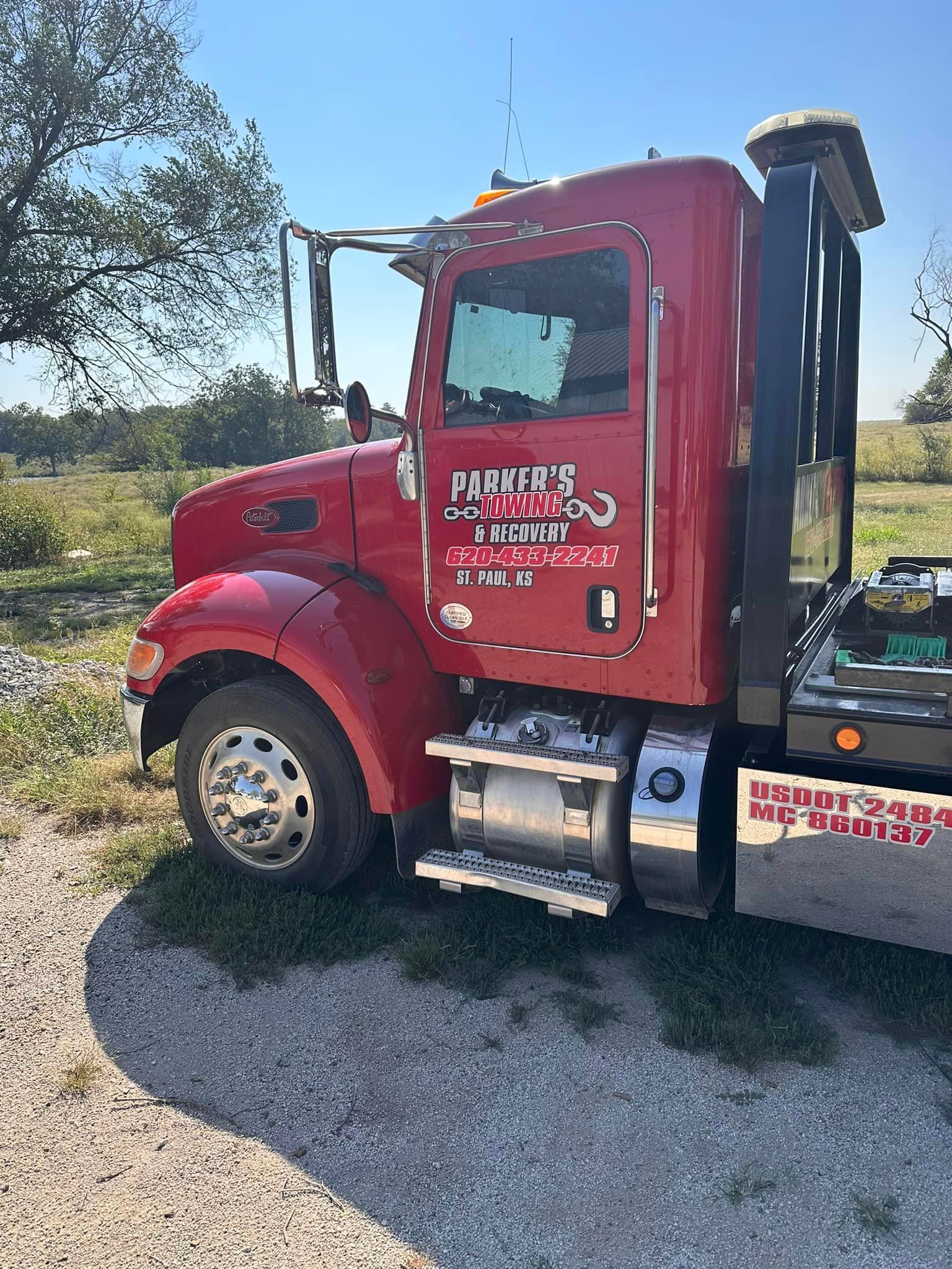 A red semi truck is parked on the side of the road.