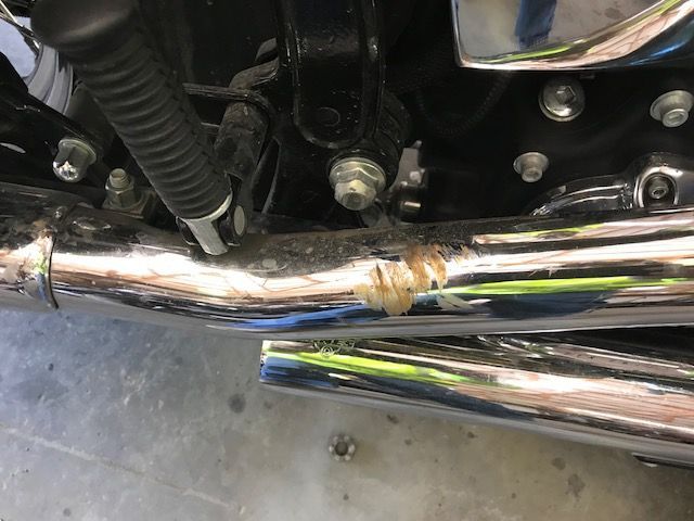 A close up of a motorcycle exhaust pipe on a concrete floor.