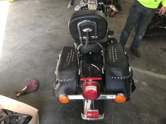A man is standing next to a black motorcycle