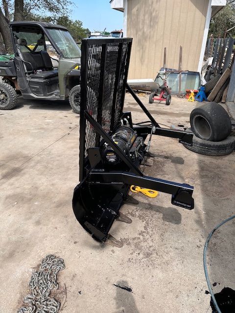 A black vehicle is parked in a parking lot next to a tractor.