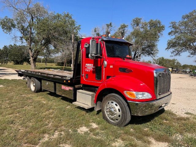 A red tow truck is parked in a grassy field.
