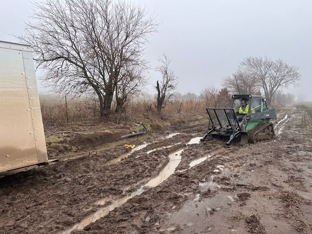 A man is driving a bulldozer on a muddy road.
