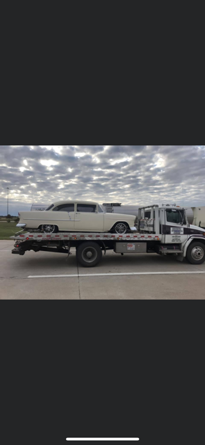 A white car is being towed by a tow truck.