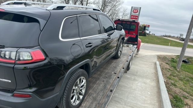 A black jeep is being towed by a tow truck.
