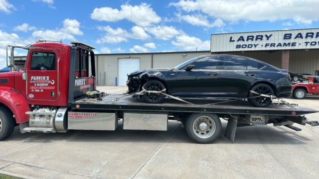 A tow truck with a black car on the back of it.