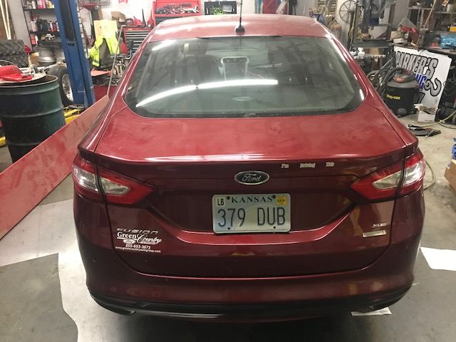 A red ford car with a kansas license plate is parked in a garage.