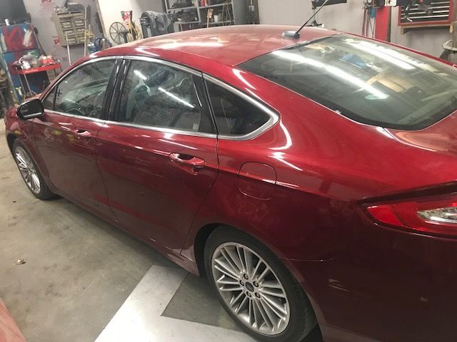 A red ford fusion is parked in a garage