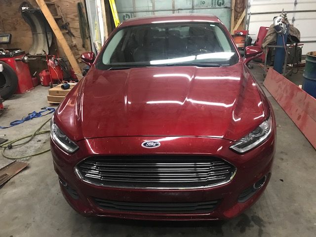 A red ford car is parked in a garage