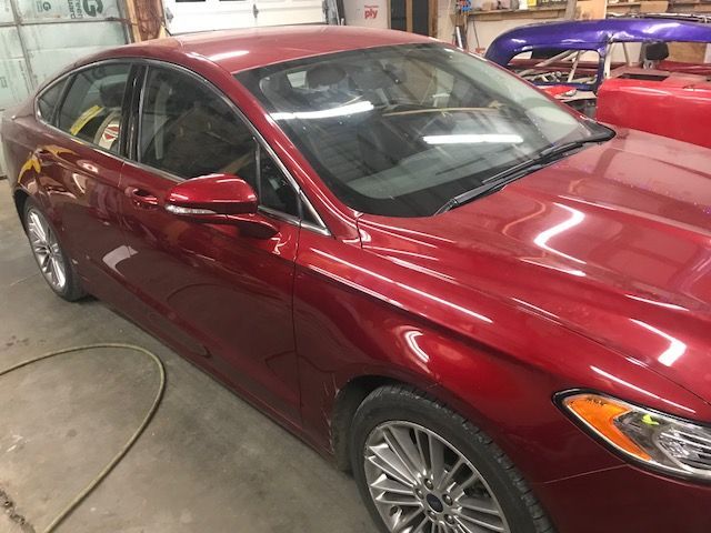 A red ford fusion is parked in a garage