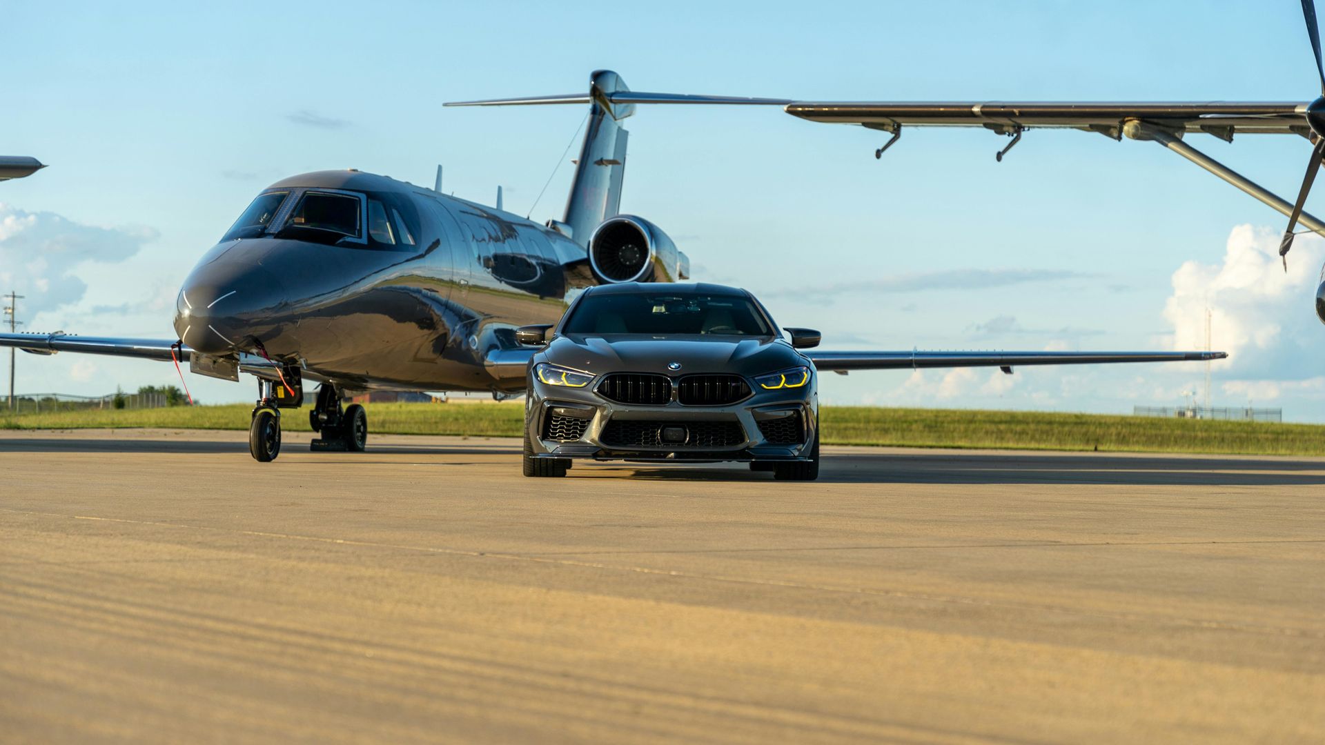 A car is parked next to a private jet on a runway.