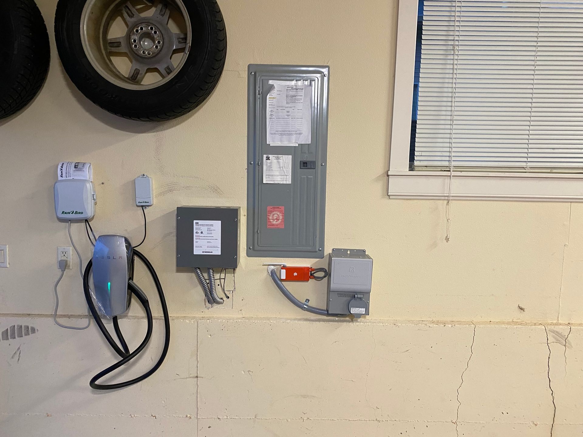 A tesla charging station is mounted on the wall of a garage.