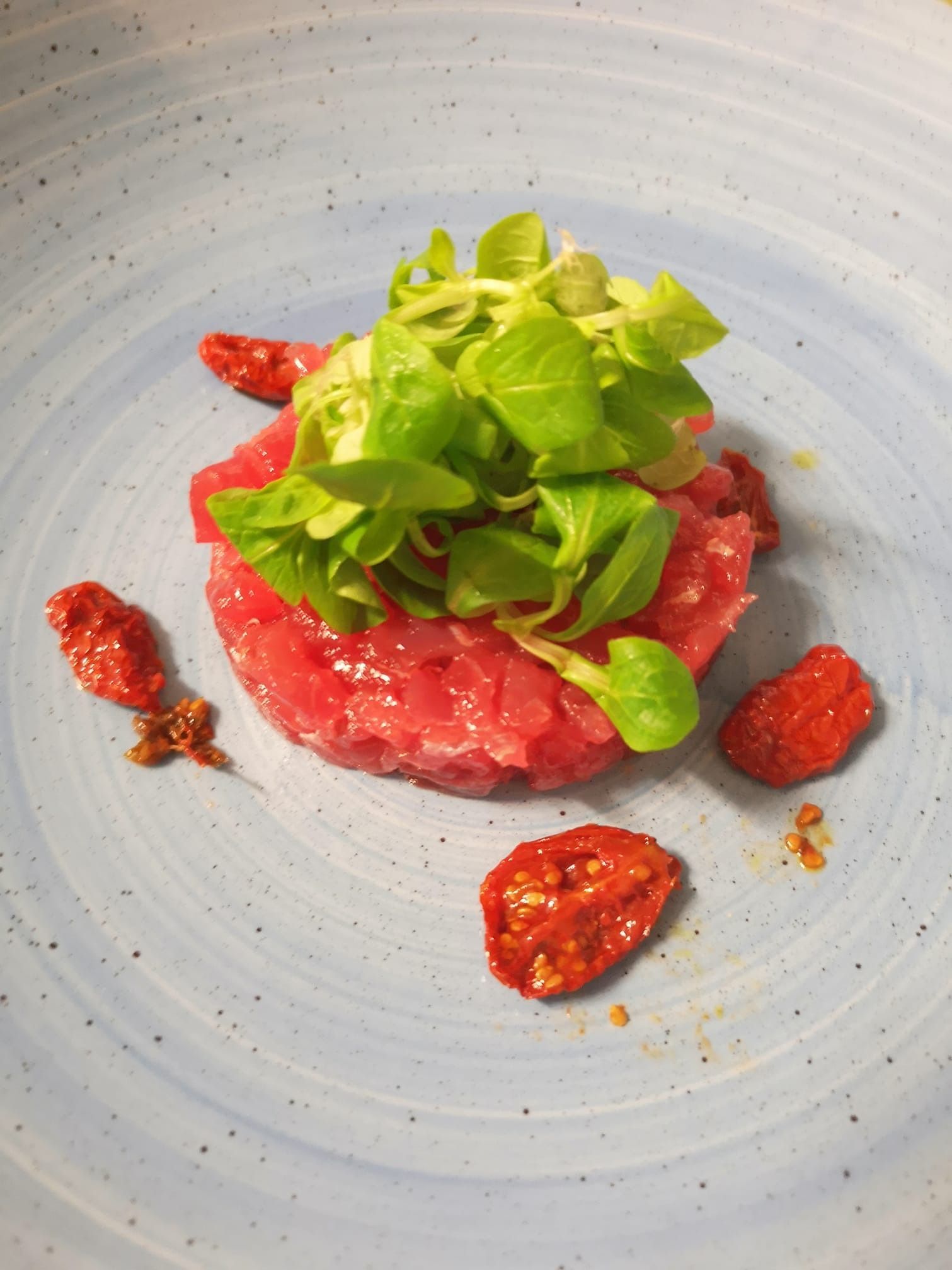 Piatto di frutti di mare con limoni e arance su un tavolo; bottiglie e bicchiere di vino sullo sfondo.