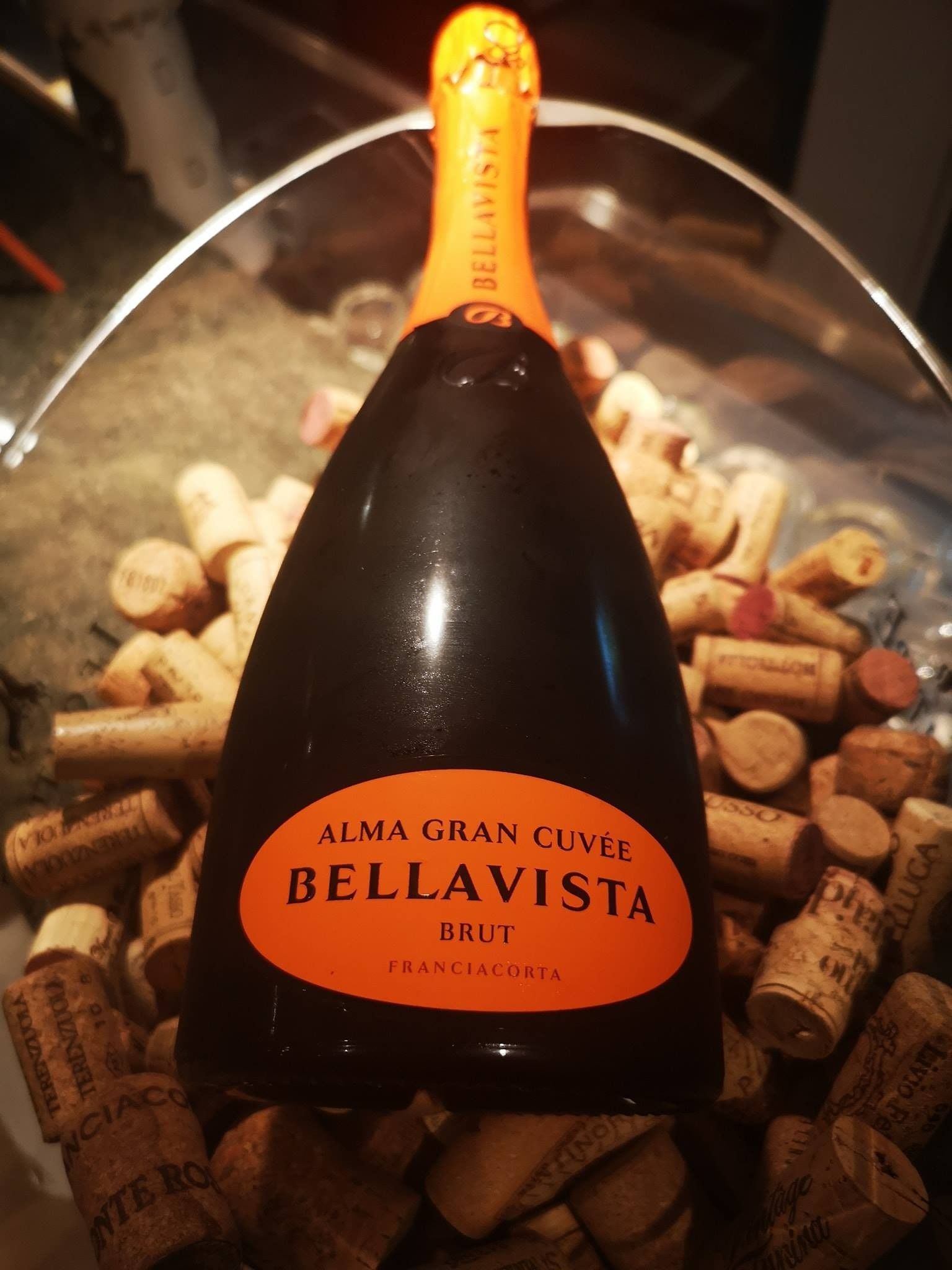 Piatto di frutti di mare con limoni e arance su un tavolo; bottiglie e bicchiere di vino sullo sfondo.