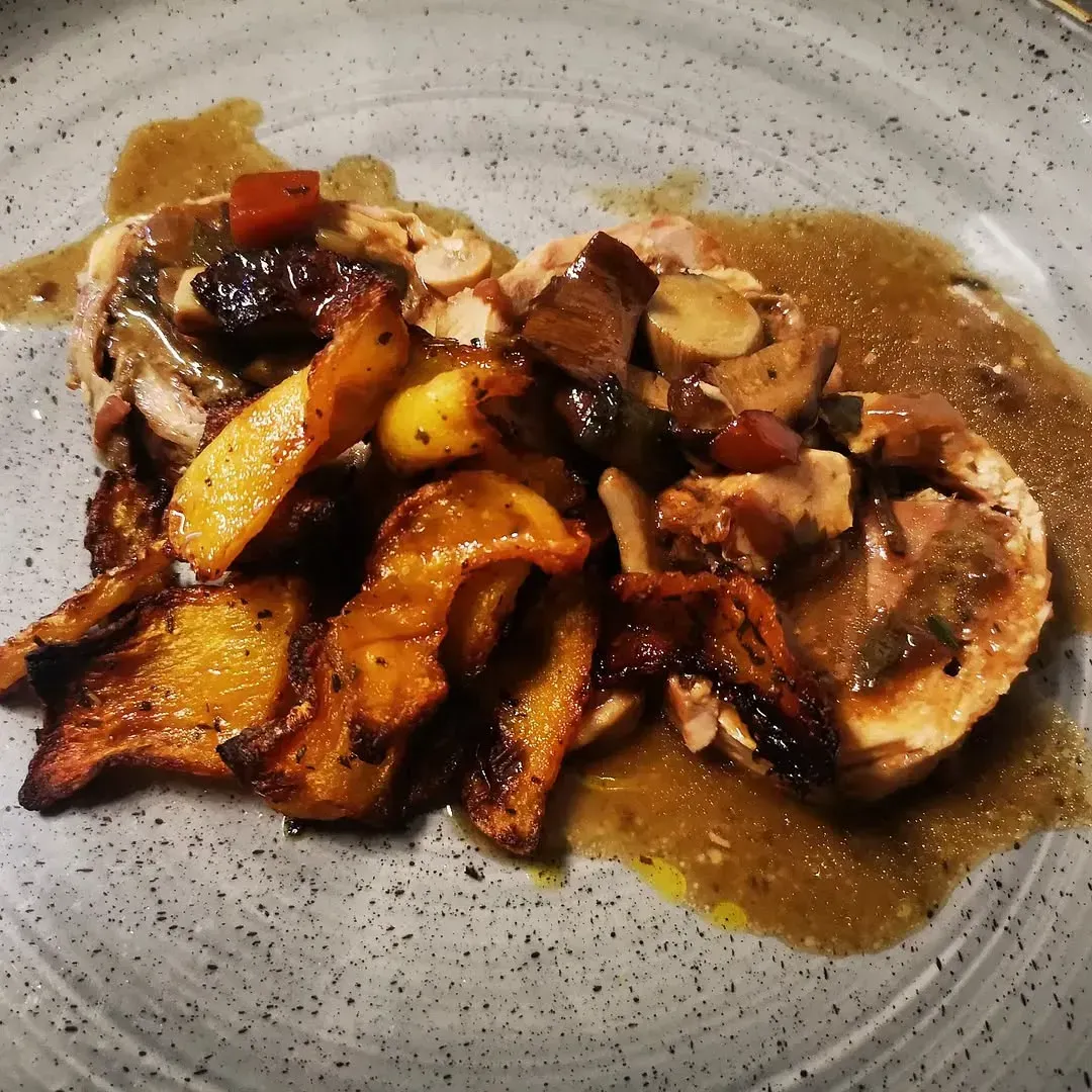 Piatto di frutti di mare con limoni e arance su un tavolo; bottiglie e bicchiere di vino sullo sfondo.