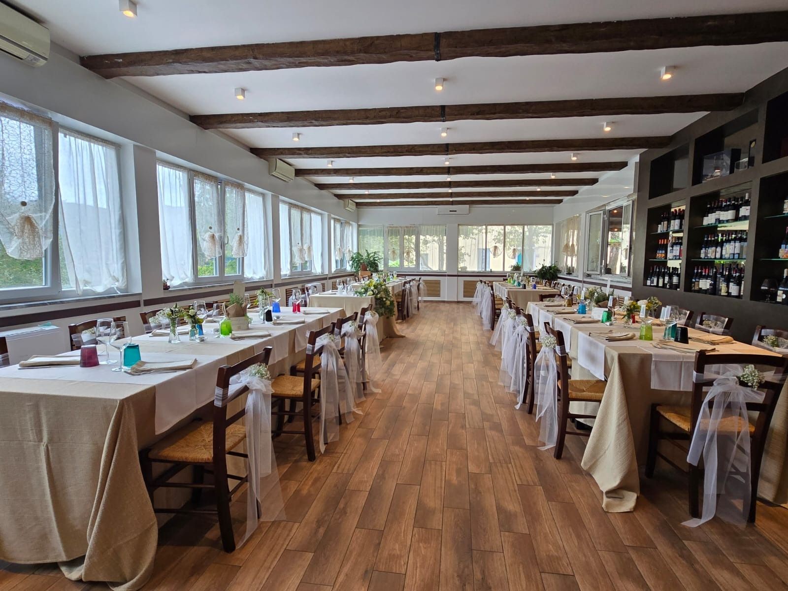 Un bicchiere di vino e una bottiglia su un tavolo. Il bicchiere è pieno di vino rosso. L'etichetta della bottiglia raffigura dei fiori blu.