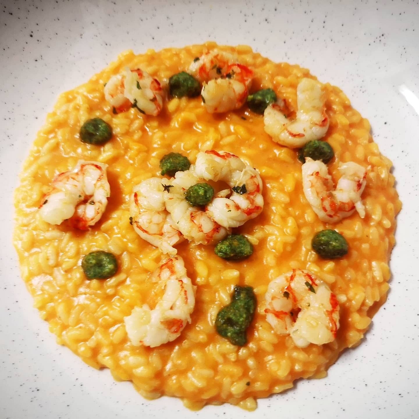 Pasta ai frutti di mare con gamberi, cozze, polpo, pomodori ed erbe aromatiche su un piatto bianco.