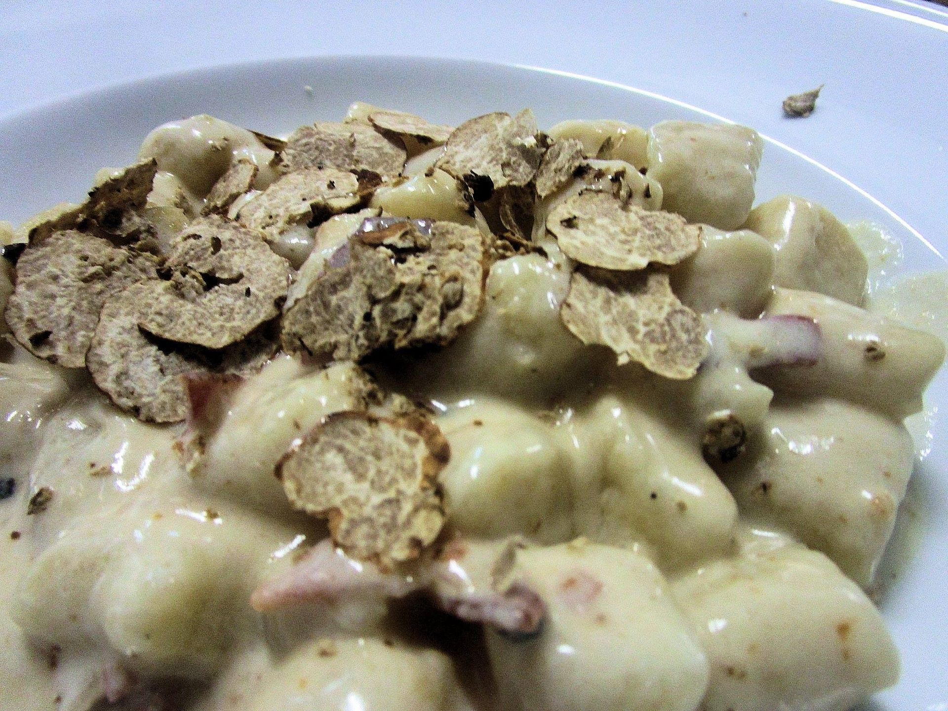 Un bicchiere di vino e una bottiglia su un tavolo. Il bicchiere è pieno di vino rosso. L'etichetta della bottiglia raffigura dei fiori blu.