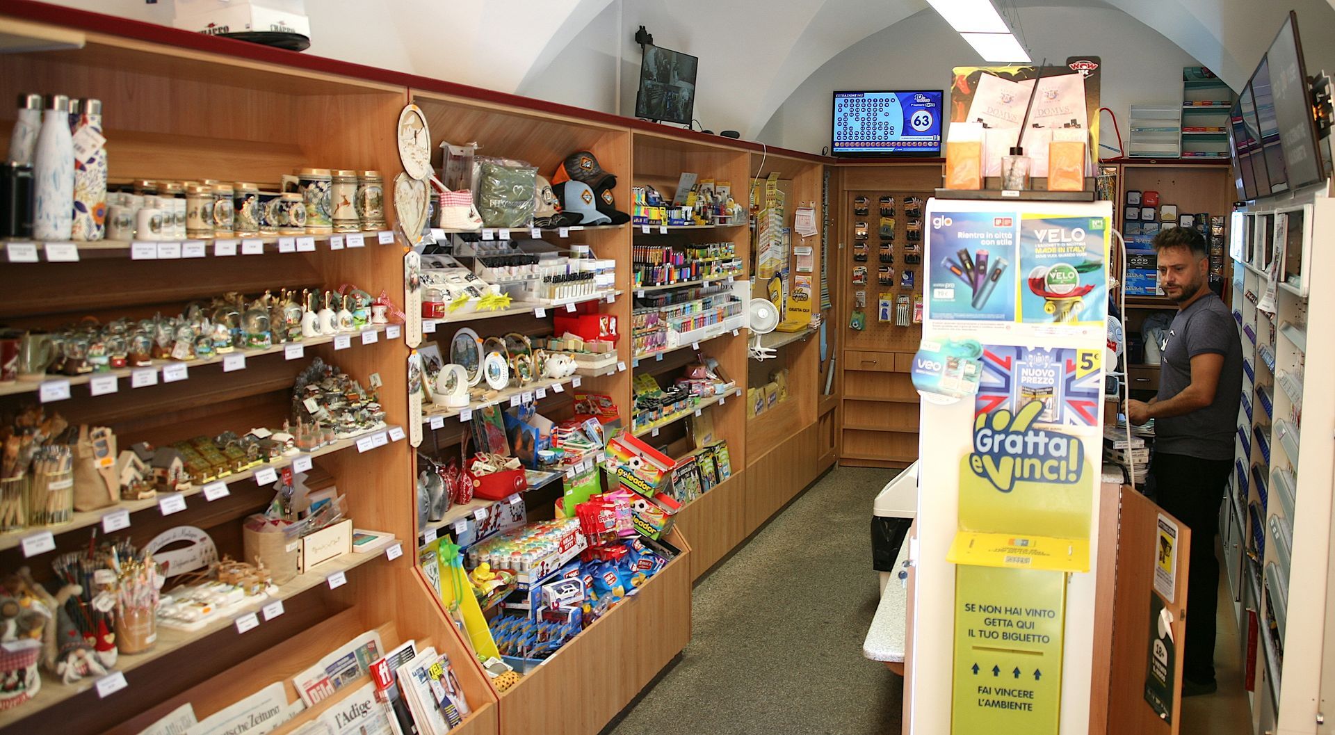 Due persone brindano con dei bicchieri di gin decorati in un bar scarsamente illuminato, festeggiando con altre persone che si intravedono sullo sfondo.