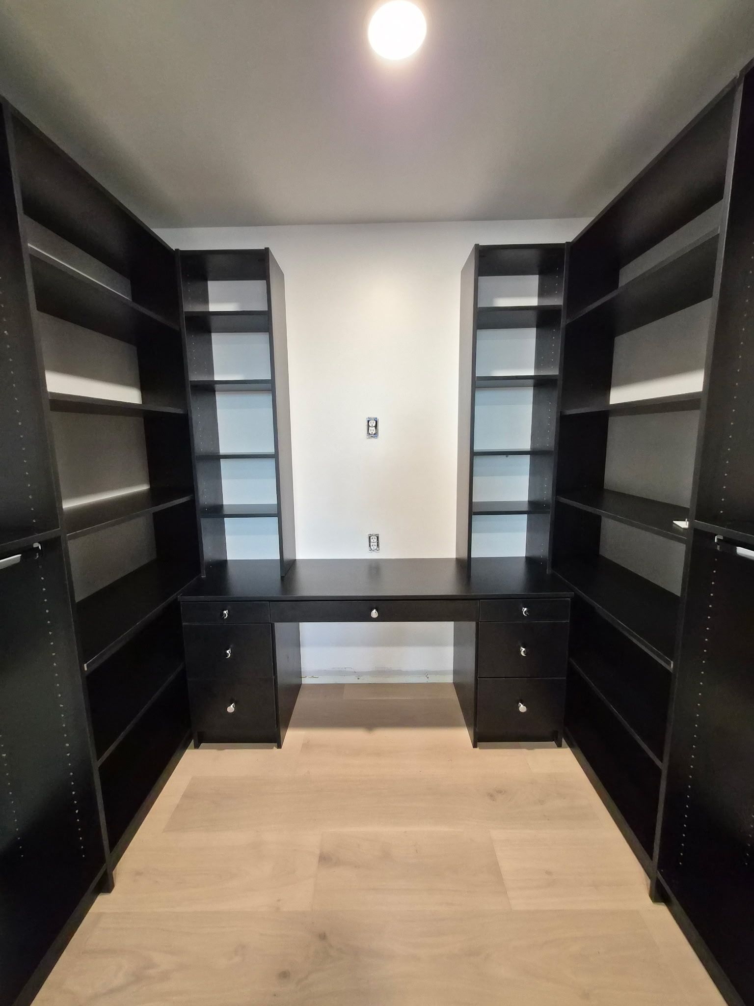 Black walk-in closet with vanity and wood floors