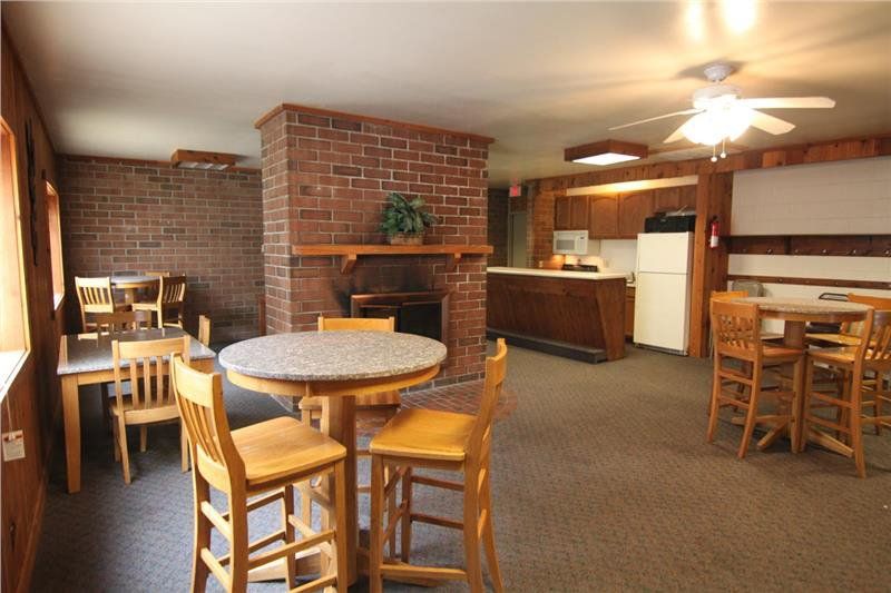The club house at Rustic Woods Townhomes includes a brick fire place, tables, chairs, and full kitchen