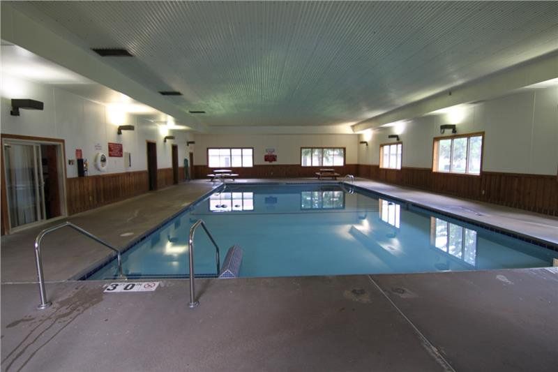 A view of the indoor pool at Rustic Woods townhomes with picnic tables in the back